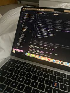 an open laptop computer sitting on top of a white bed next to a keyboard and mouse