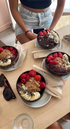 three bowls of desserts are on the table with sunglasses and strawberries in them