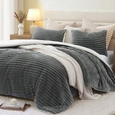 a bed with grey and white comforters in a bedroom