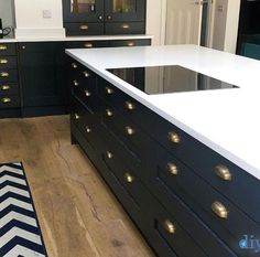 a kitchen with black cabinets and white counter tops, gold knobs on the drawers