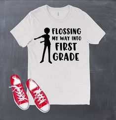 "It's that time again! Back to school we go! What better way to go than dressed in this awesome back to school design. The design is made on a white or black short sleeve tee with black or white heat transfer vinyl for the words \"Flossing my way into -- Grade\". Let us know in comments to seller which color shirt you want. This shirt would also be perfect for teachers too! Choose your grade level from the options! Youth Sizes: XS - 5T Small 6-7 Medium 8 Large 10-12 Adult Sizes: X-small Small Me Fun School Tops With Funny Text, Funny Text Print Tops For School, Casual Tops For End Of School Year Events, Funny Short Sleeve Tops For College, Casual Short Sleeve Shirt For School Events, College Tops With Funny Text For School Spirit, College Tops With Funny Text And School Spirit, Fun Text Print Shirt For School, Fitted Letter Print T-shirt For School