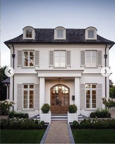 a large white house with lots of windows and shutters on the front door is shown