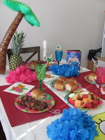 a table topped with plates and food next to a palm tree on top of a white table cloth