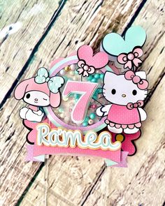 a hello kitty birthday cake topper on a wooden table