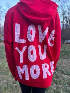 a person wearing a red hoodie with the words love you more printed on it