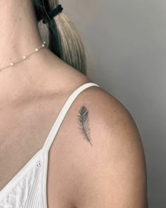 a woman with a small feather tattoo on her left upper arm and back of the shoulder