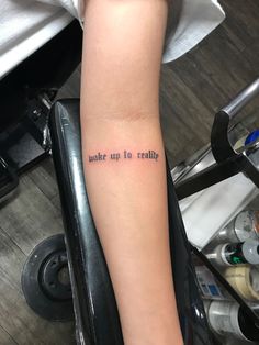 a woman's arm with the words wake up to reality on her left forearm