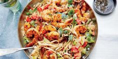 a pan filled with pasta and shrimp next to broccoli on top of a table