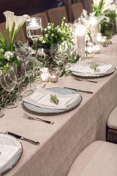 the table is set with place settings and flowers in vases, candles, and napkins