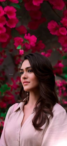 a woman standing in front of pink flowers with her eyes closed and looking off to the side