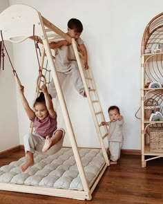 two children playing on a wooden swing set in the living room while another child watches