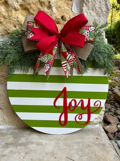 a green and white striped christmas ornament with a red bow hanging from it's side