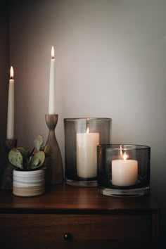 three candles sitting on top of a table next to a vase with succulents