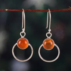 Mysterious and magical, Sapna Mehta's newest design captures the beauty of the universe and combines it with glamour. As an expert in jewelry creations, the designer works with Indian artisans to create these dangle earrings, whose round formations are made from polished sterling silver. The touch of uniqueness is in the warm-toned carnelian stones set at the center, symbolizing courage with their intense light. Elegant Carnelian Earrings, Carnelian Drop Earrings Jewelry Gift, Carnelian Drop Earrings As Gift, Carnelian Drop Earrings For Gift, Round Carnelian Earrings, Nickel-free Carnelian Jewelry, Carnelian Gemstone Dangle Earrings, Amber Gemstone Drop Earrings, Amber Carnelian Gemstone Earrings