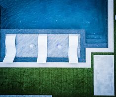 an abstract painting of a bench in front of a blue wall and green grass area