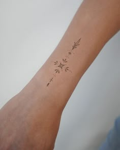 a person's arm with a tattoo on it that has flowers and leaves drawn on it