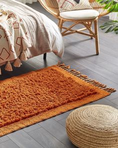 an orange rug on the floor next to a bed