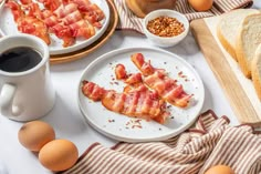 bacon strips are arranged on plates next to bread and coffee