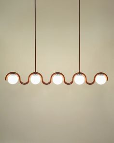 three lights hanging from the ceiling in a room with white walls and brown flooring