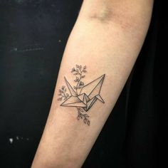 a tattoo with an origami bird on it's arm and some leaves