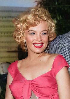 a woman in a pink dress smiling at the camera