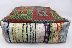 two multicolored pillows sitting next to each other on top of a white surface