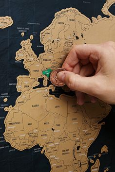 a person holding a tiny green object in front of a world map on a black surface