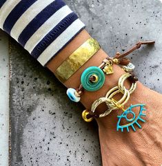 Elevate your accessory game with this stunning boho chic bracelet set. Featuring a blend of turquoise and gold tones, this set includes a handmade adjustable cord bracelet adorned with turquoise donuts and evil eye charms, paired with a hammered brass cuff. Perfect for adding a touch of bohemian elegance to any outfit. Ideal for summer fashion, festival wear, and unique gift ideas for her. Adjustable Eclectic Bracelets For Beach, Bohemian Resizable Cuff Bracelet For Gift, Turquoise Bohemian Bracelets, Bohemian Turquoise Hand Wrapped Bracelets, Bohemian Resizable Cuff Bracelet As Gift, Bohemian Resizable Cuff Bracelet Gift, Gold Bohemian Friendship Bracelets, Hippie Turquoise Bracelets For Festival, Bohemian Festival Jewelry With Bracelet Strap