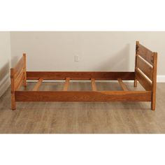 a wooden bed frame sitting on top of a hard wood floor next to a wall