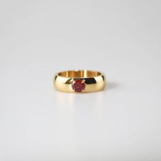 a gold ring with a red stone in it