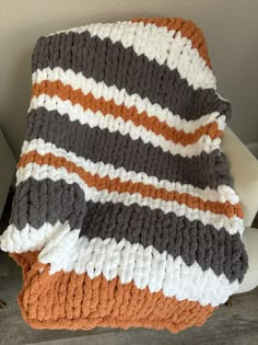 an orange and gray blanket sitting on top of a white chair