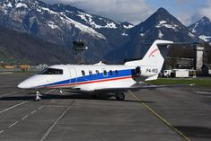 an airplane is parked on the tarmac in front of mountains