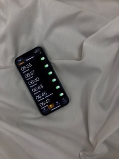 a cell phone laying on top of a white sheet with green buttons and time zones