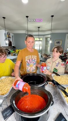 a group of people standing around a table filled with food and condiments on it