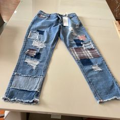 a pair of blue jeans with patches on them sitting on top of a white table