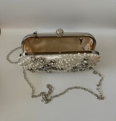 The Pearl Purse is a stylish blend of sophistication and glamour. It is crafted with precision and attention to details. This beaded purse is a must have addition to your accessory collection. It will glamorize your look and is spacious enough to carry all the essentials. The clutch comes with a detachable chain strap so you can carry it as a clutch or a shoulder & crossbody bag. Dimensions: (LxHxW): 7.5 inches x 4.7 inches x 1.97 inches Material: Pearls and Beads, Satin, Rhinestones Features: K Luxury Embellished Pearl Bag, Chic Pearl-embellished Clutch For Formal Occasions, Handheld Clutch With Pearl Handle, Luxury Beaded Shoulder Bag For Events, Chic Pearl Clutch For Party, Luxury Pearl-embellished Clutch For Formal Occasions, Luxury Pearl Embellished Clutch For Formal Occasions, Luxury Pearl Embellished Clutch For Formal Events, Luxury Pearl Evening Bag For Party