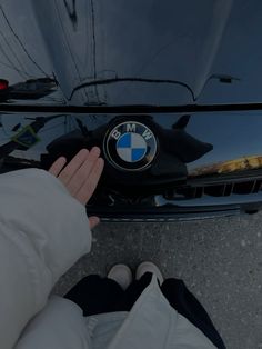 someone's hand on the hood of a bmw car