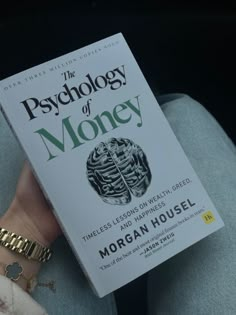 a person holding up a book in their hand with the title, the psychology of money