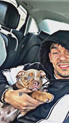 a man sitting in the back seat of a car holding a small dog