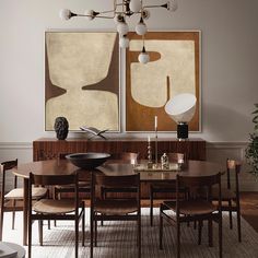 a dining room table and chairs in front of two paintings