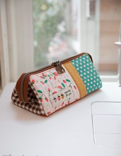 a purse sitting on top of a table next to a sewing machine and window sill