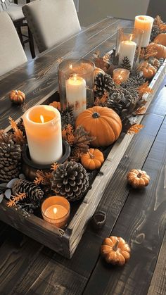 a wooden table topped with candles and pumpkins