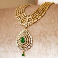 An heirloom of divinity, crafted through the ages! Introducing an opulent fiver-layer kundan mala, adorned with a magnificent emerald stone centerpiece that exudes timeless elegance, this set blends the regal charm of kundan with the vibrant allure of emeralds. A masterpiece of craftsmanship, it promises to elevate any occasion with its majestic allure. The listing includes long mala and a pair of matching earrings. Gold-plated on high-quality brass as base metal. Made by order. Kindly allow 5-7 Elegant Hand Set Kundan Necklace For Rituals, Elegant Kundan Necklace For Rituals, Kundan Emerald Necklace For Wedding And Festivals, Wedding Kundan Emerald Necklace For Festivals, Emerald Chandbali Necklace With Kundan For Wedding, Festive Heavy Kundan Emerald Necklace, Ceremonial Kundan Emerald Necklace For Festive Occasions, Festive Emerald Kundan Chandbali Necklace, Festive Chandbali Kundan Necklace With Emerald