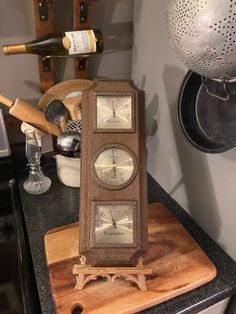 a clock sitting on top of a wooden cutting board next to a bottle of wine