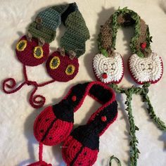 crocheted hats and scarves are laid out on a white sheet with green stems