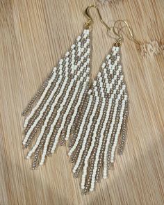 "High-shine, gold-lined, AB clear beads and matte cream beads in a fun geometic pattern. Classic look, great for everyday wear or to dress up your holidays. 🎄❄️✨ Length: Approximately 4.5\" Width: 1\" Length is measured from top of ear wire to the bottom of the fringe. Width is measured at the widest point of the earring. These earrings were hand beaded using my own original design, with 11/0 TOHO seed beads, Wildfire & Nymo threads. Gold plated Surgical Steel Findings. Care instructions: ⦿ Store your beaded earrings out of direct sunlight, either by hanging or laying them flat. ⦿ Clean your beads with a soft brush or cloth when necessary. ⦿ If your earrings feature matte finished beads, you may lightly wipe them with rubbing alcohol to restore the matte finish. ⦿ Clean the ear hooks/wire Stitch Earrings, Beaded Fringe Earrings, Brick Stitch Earrings, Clear Beads, Jolly Holiday, Earrings Christmas, Gold Cream, Gold Line, Rubbing Alcohol