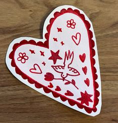 a paper cut out of a heart with hearts and stars on the side, sitting on a wooden surface