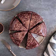 a chocolate cake sitting on top of a table next to a cup of coffee and silverware