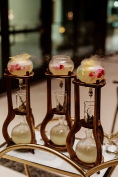 three glass vases filled with liquid sitting on top of a metal tray next to each other