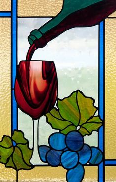 a stained glass window with grapes and wine being poured into it by a green bottle